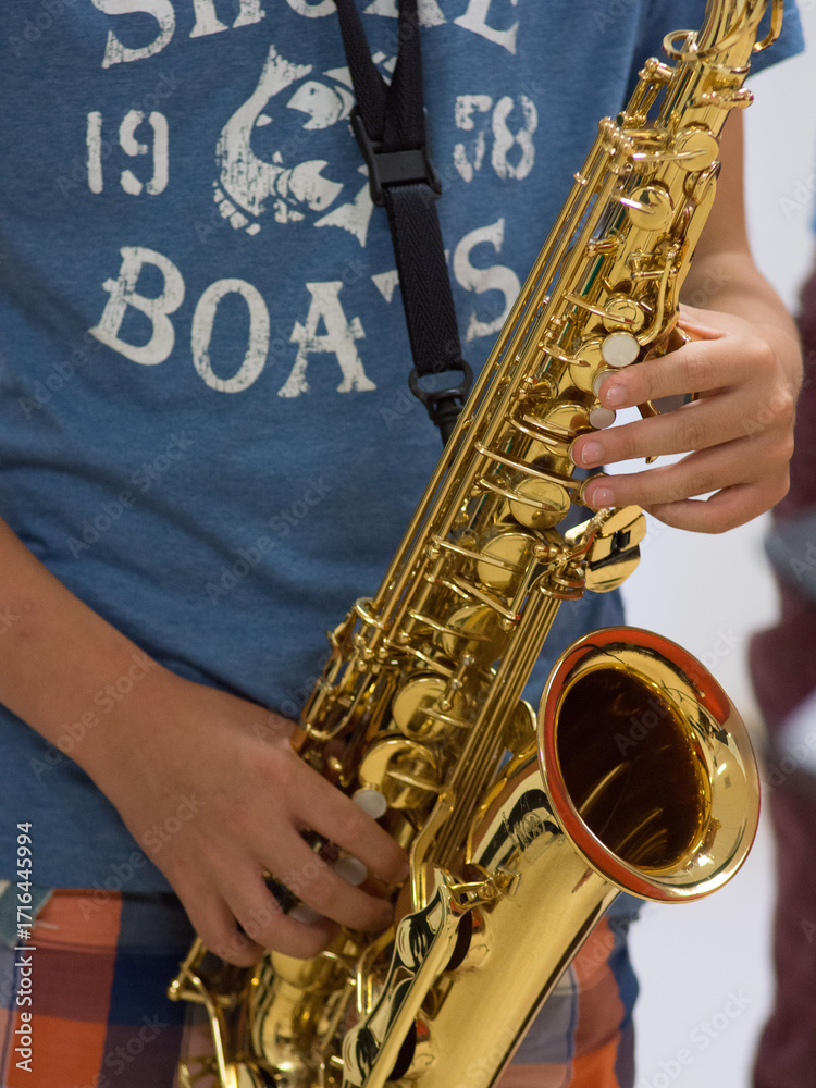 Obraz premium Human hand holding playing a saxophone close up with another saxophone in the background during musiclessons