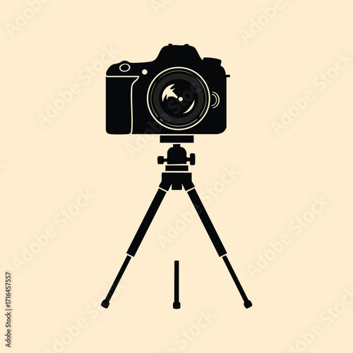 Black silhouette of a professional camera mounted on a tripod with adjustable legs on a beige background