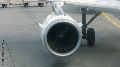 Aircraft engine viewed from the side, showcasing the intricate turbine design and surrounding components, highlighting the powerful machinery in action on the tarmac