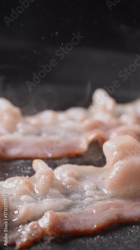 Camera follows cooking bacon on grill. Shot with high speed camera, slow Motion.