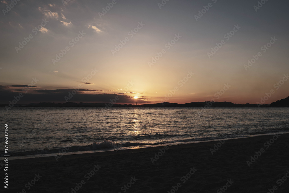 Fototapeta premium 渋川海岸、美しい夕日が海岸線に沈む風景、岡山、日本