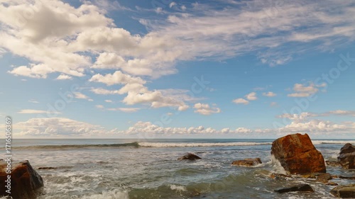 Waves crashing onto the shore with fallen rock fragments after a storm, real-time video of the sea with the horizon obscured by clouds, a calm view of the turbulent ocean