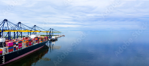 Panorama view of international containers cargo ship at industrial import-export port transport goods around world, global transportation and logistic business.Oversea international Business.