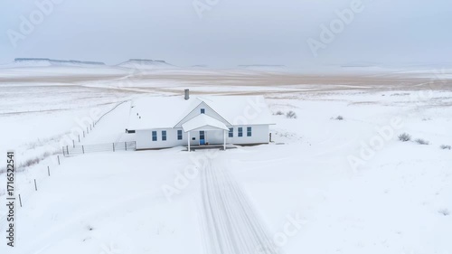 Drone view of snowy field and solitary house by the road — winter landscape, roads and isolated farmhouse.