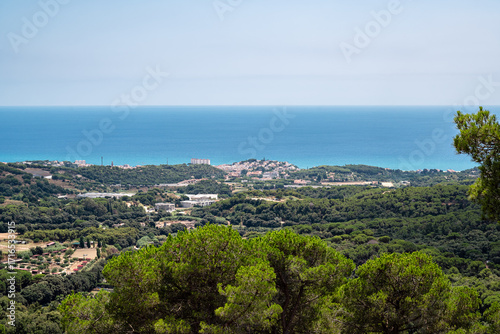Landscape with the blue Mediterranean Sea and a coastal resort town on a bright summer day with a cloudless sky.