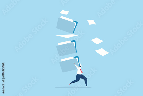 Man struggling to carry a tall stack of folders and papers flying around him