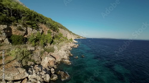 FPV aerial of rocky cliffs and blue Adriatic Sea at Sveta Nedelja, Hvar, Croatia. Coastal landscape with forest and clear water.