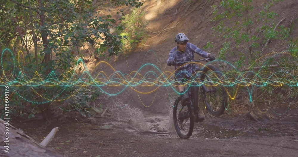 Fototapeta premium Riding trail bike wearing helmet and goggles splashing through forest creek, with digital waveforms