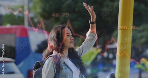 Raising hand female commuter signalling bus at stop pole with backpack smartwatch and stock charts