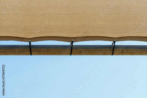 Tan Shade Fabric Attached to Metal Pipe with Zip Ties