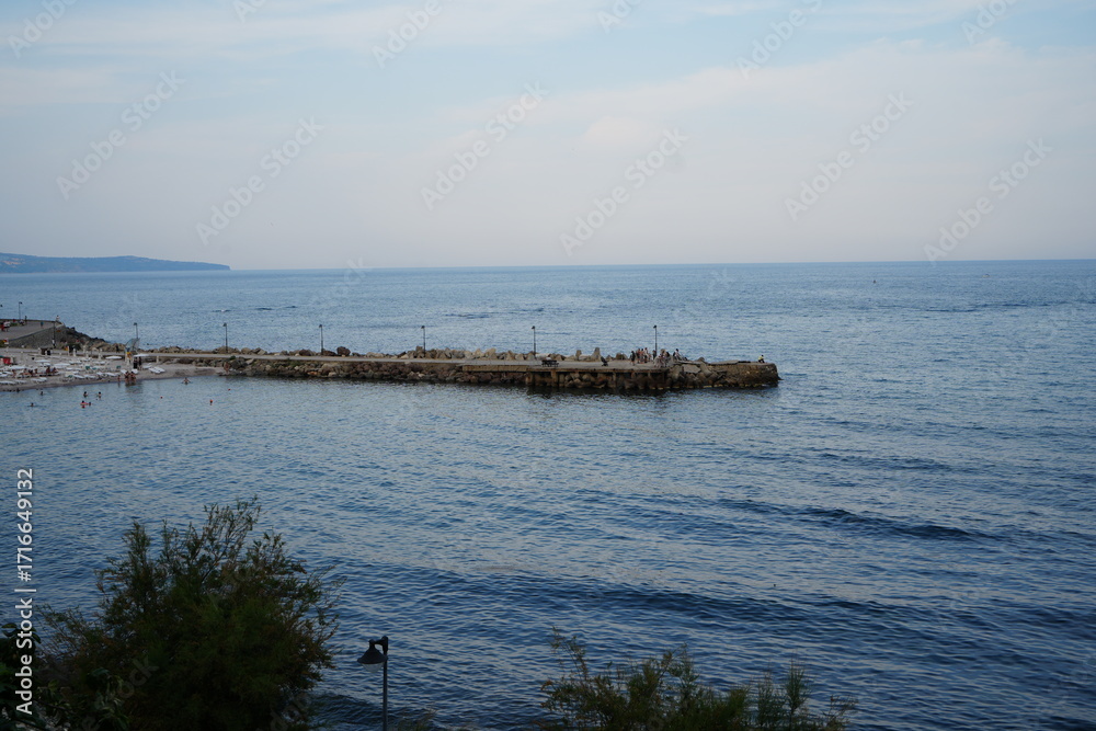 Obraz premium Stone breakwater in calm sea near Nessebar, Bulgaria. Blue water and sky creating peaceful coastal landscape with minimal composition.