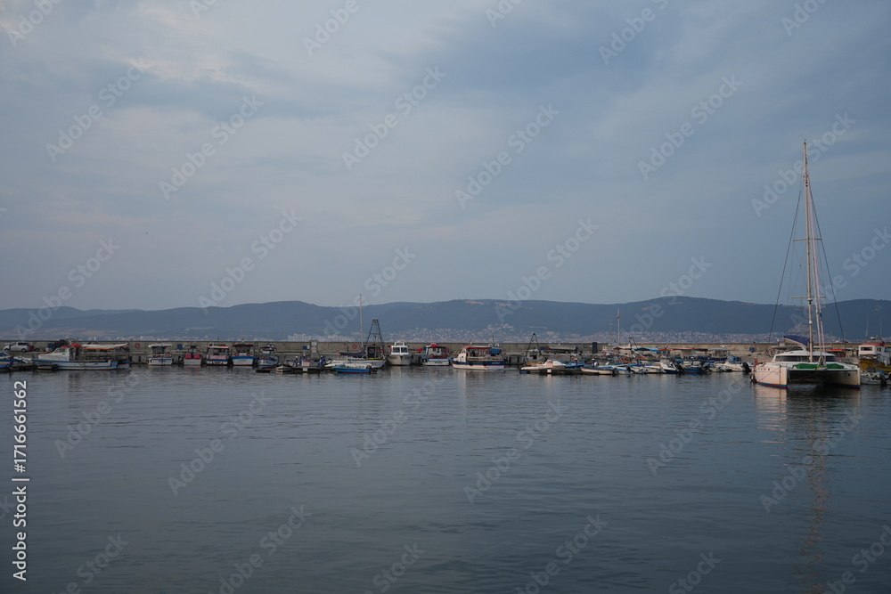 Fototapeta premium Calm sea view with cloudy sky and distant coastline. Peaceful seascape at dusk — concept of travel, tranquility, nature, and coastal landscape.
