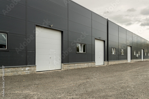 Facade of a modern warehouse or industrial building made of sandwich panels with roller doors.
