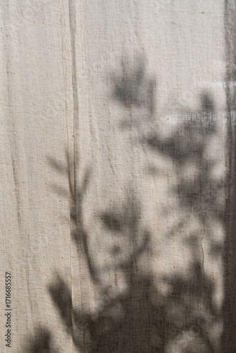 Floral sunlight shadows on a neutral beige linen curtains, aesthetic minimalist natural background with copy space	