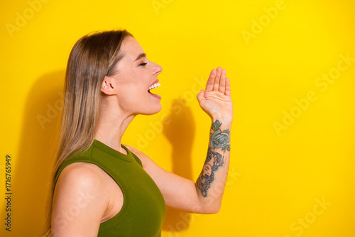 Young woman in khaki top posing against a vibrant yellow background, expressing positivity and cheerfulness with an energetic demeanor