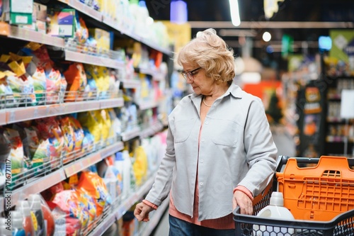 Fotografi Elderly woman buying household chemicals or laundry detergent at supermarket