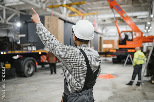 Construction worker directing crane operations in modular house factory