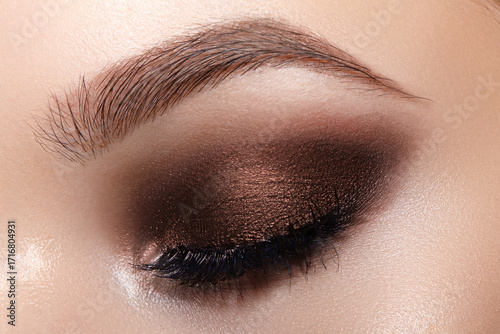 Macro beauty of eye makeup. Beautiful fashion evening eyes make-up. Holiday makeup detail with long eyelashes and perfect brow. Close-up of festive female eye make up in smokey eyes style