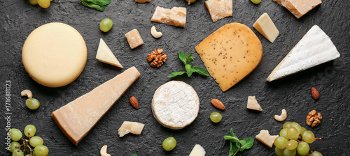 Tableau sur toile Different types of tasty cheese, grapes and nuts on dark background