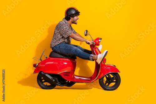 Funny man riding a red scooter on a vibrant yellow background, exuding joy and energy in a casual and stylish outfit