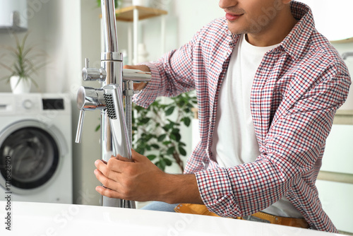 Professional plumber installing modern chrome faucet in kitchen or bathroom, ...
