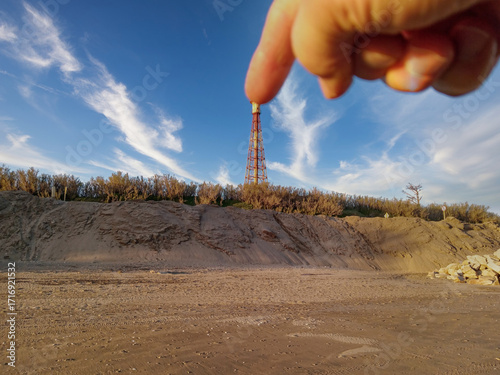 Hand creating forced perspective optical illusion on beach