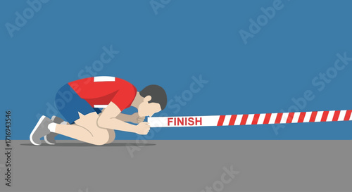 A determined athlete lunges forward, head bowed, pushing through the finish line tape in a moment of intense athletic exertion.