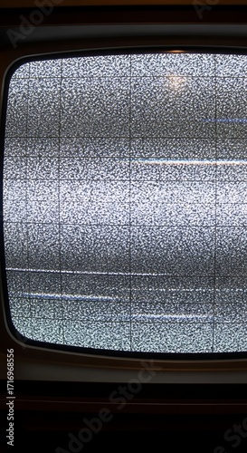 A close-up view of a vintage television screen displaying static and a fractured glass surface, showcasing a fragmented, muted grey and white design.