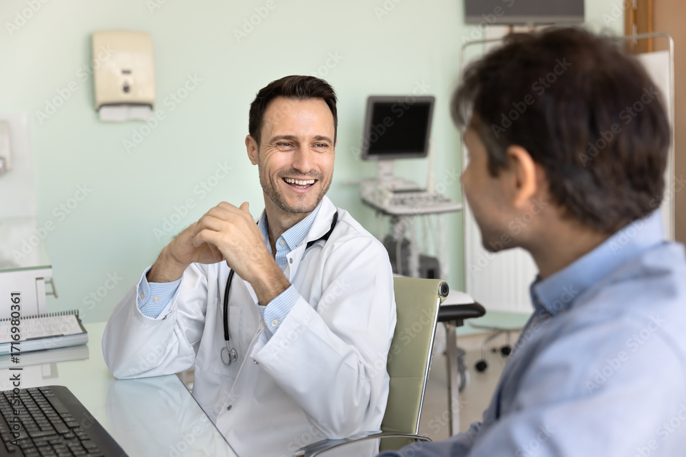 Fototapeta premium Friendly middle aged doctor hold casual conversation with male patient