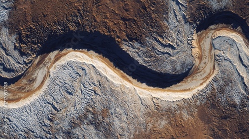 Aerial view of a winding river cutting through arid terrain with distinct sediment patterns
