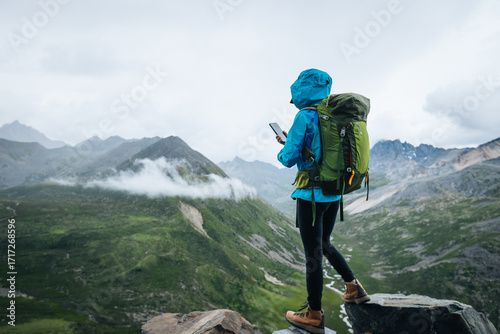 Hiking woman taking photo with smart phone  on high altitude mountain top