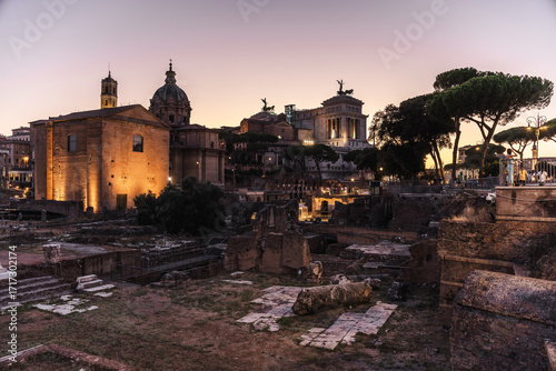 Fotografija Roman Forum ruins with illuminated historical buildings and monuments at dusk in
