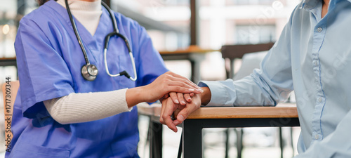 Young nurse caring patient with hand support, compassionate healthcare worker offering comfort and reassurance in clinic setting