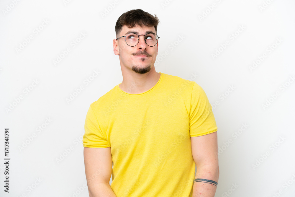 Obraz premium Young caucasian handsome man isolated on white background having doubts while looking up