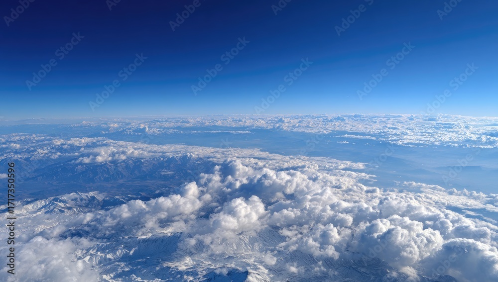 Naklejka premium High-altitude view of clouds, mountains, and a vast blue sky