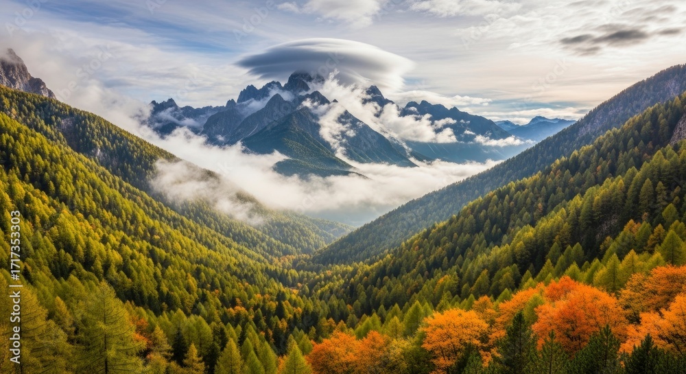 Fototapeta premium A vast mountain valley with dense evergreen and autumn-colored forests dramatic peaks veiled in mist and a distinctive lenticular cloud overhead