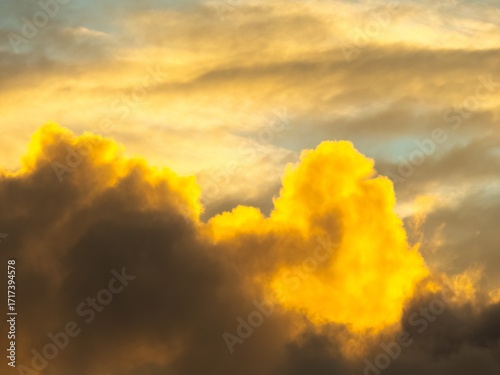 cumulus clouds against a blue sky, illuminated by the orange rays of the setting sun on a sunny summer evening
