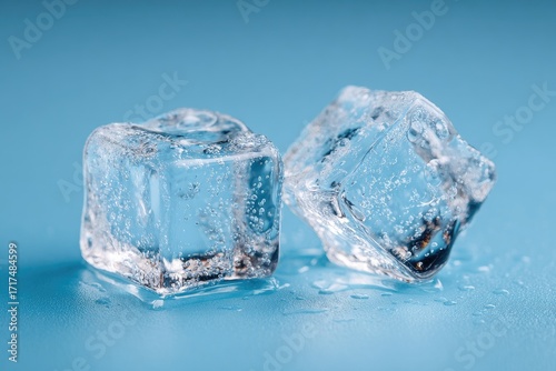Close-up of two clear ice cubes on a blue surface