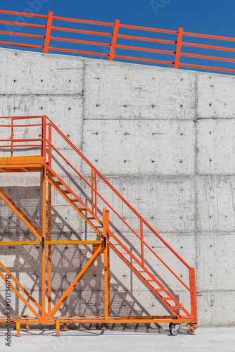 Orange Metal Staircase Against Concrete Wall and Clear Blue Sky