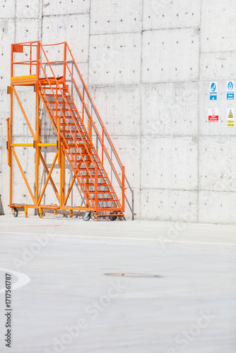 Orange Metal Staircase Against Concrete Wall and Clear Blue Sky