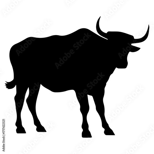 Silhouette of a large bull standing with curved horns and a short tail in a side profile view image