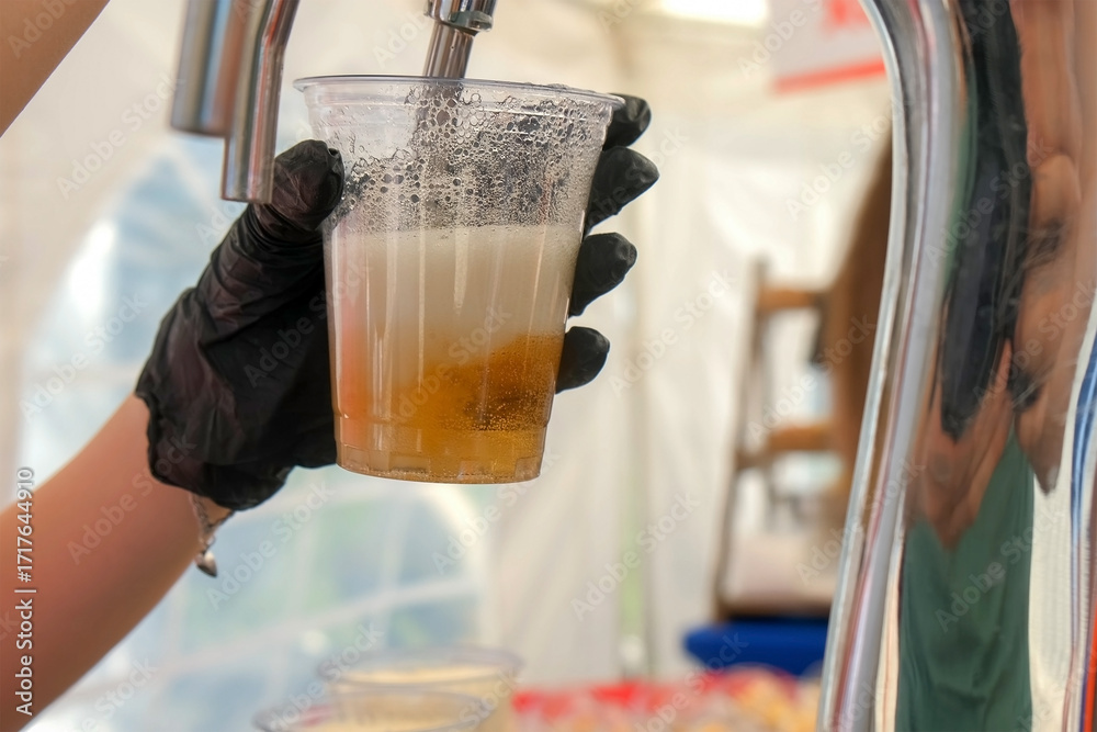 Φωτογραφία Bartender pouring fresh golden alcohol beer from tap in plastic cup in street cafe