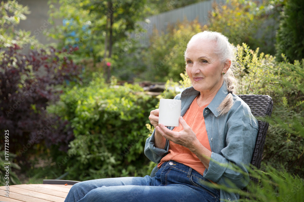 Obraz premium portrait of a cheerful elderly woman with a cup of tea in the garden about her home on a summer. concept without stress. mental health. Enjoying the little things. Mindfulness and feel-good moments.