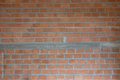 A partially constructed red brick wall with visible grey mortar and steel reinforcing bars  rebar   indicating
