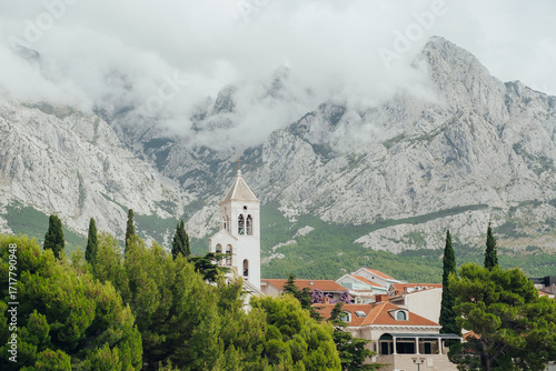 Church Tower in Scenic Mountain Village with Dramatic Cloudy Peaks