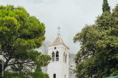 Church Tower in Scenic Mountain Village with Dramatic Cloudy Peaks