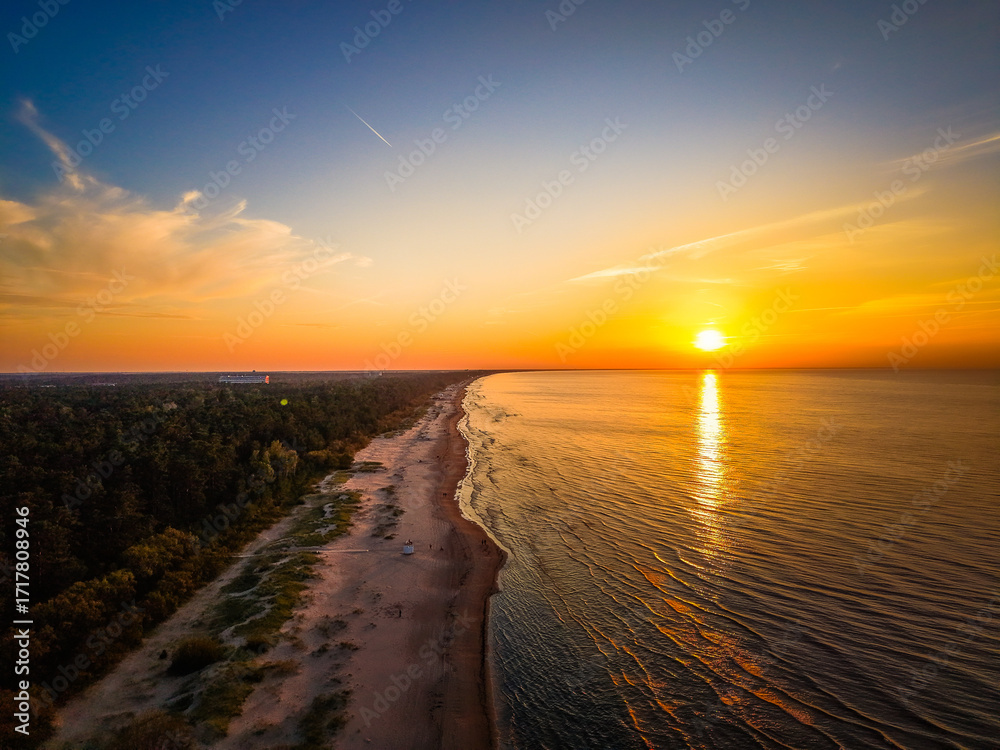 Φωτογραφία A breathtaking aerial view of a serene sunset over a sandy beach, with the sun c