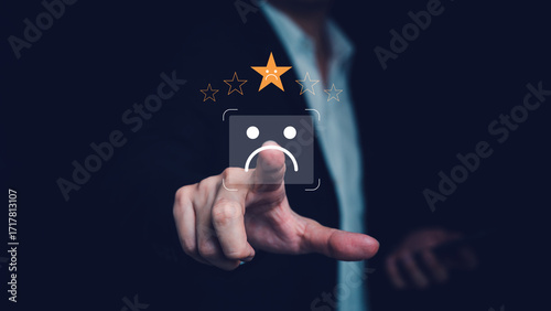 Business person touching a virtual sad face and one star rating on black background, showing poor customer satisfaction, negative review, complaint feedback, and brand risk in product or service