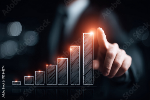 Man in suit pointing at colorful bar graph indicating upward trend