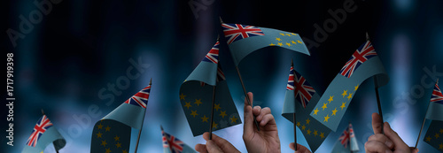 Tuvalu flags in their hands on a blurred urban background